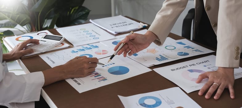 Two Asian businesswomen analyzing financial reports and graphs. Concept of financial analysis and business planning.