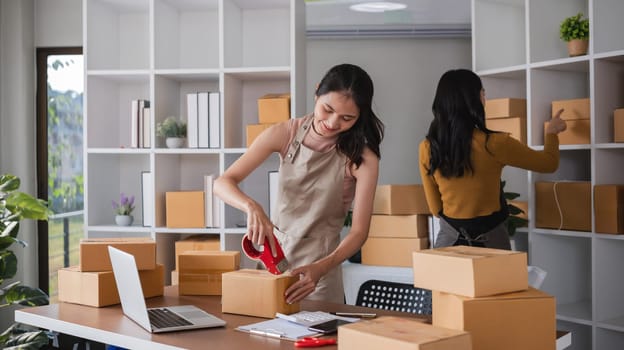 Young women working in warehouse, packaging and organizing boxes for shipping and inventory management.