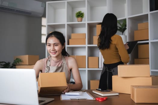 Young women working in warehouse, packaging and organizing boxes for shipping and inventory management.