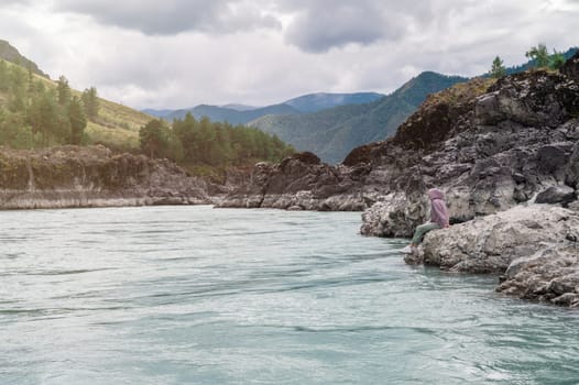 Woman at the river Katun at summer day. Trip on Altai Mountains in Altai Republic