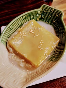 Exotic mango custard over sticky rice Asian dessert in a textured green bowl, served in a Fort Wayne Thai cafe.