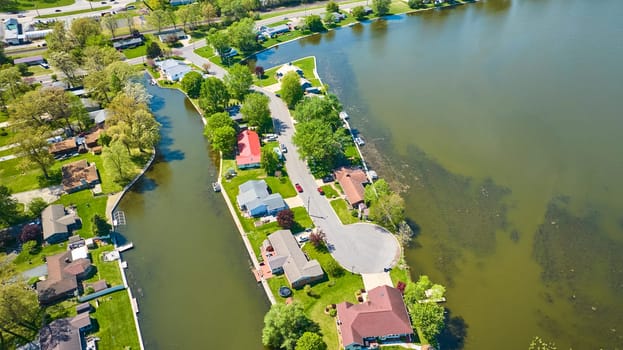 Aerial view of a peaceful suburban neighborhood by a lake in Warsaw, Indiana, showcasing lush landscapes and waterfront homes.