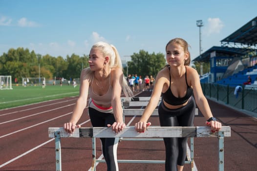 Two friends - athlete young woman runner train at the stadium outdoors
