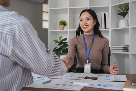 Two Asian businesswomen shaking hands in the office. Concept of partnership and agreement.