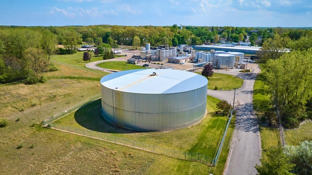 Aerial view of a large industrial complex with storage tanks in Warsaw, Indiana, showcasing the blend of industry and suburban scenery.