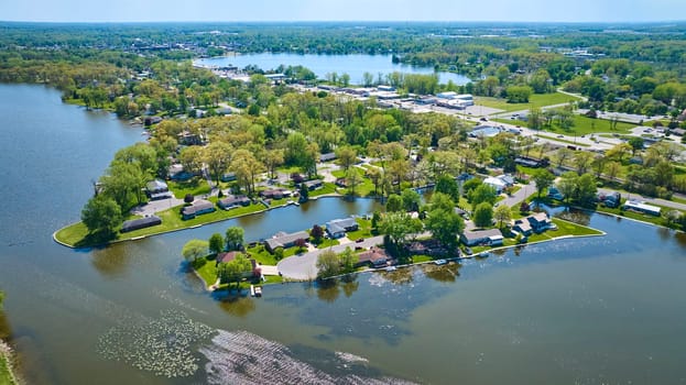 Aerial view of a peaceful suburban neighborhood by the river in Warsaw, Indiana, showcasing waterfront homes with private docks.