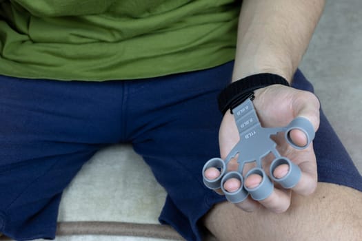 Silicone finger trainer on man's hand is ready to perform exercises to strengthen the hand, improve finger strength and mobility