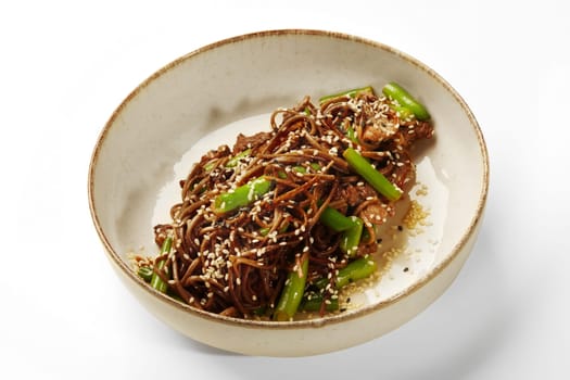 Savory soba noodle dish with fried tender beef strips, crunchy green beans, and sprinkle of sesame seeds served in ceramic bowl on white background. Simple tasty Japanese style meal