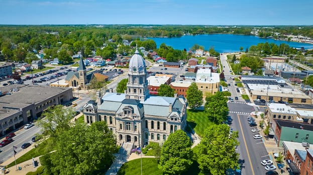 Aerial view of Warsaw, Indiana showcasing the historic Kosciusko County Courthouse and serene lake.