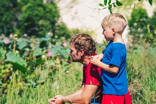 Father son study plants, looking on buds flower bud leaves stamens petals. Natural sciences, family education. Happy childhood parenthood harmony.