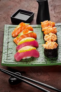 Exquisite selection of nigiri and gunkan sushi with salmon and tuna elegantly served on textured green ceramic plate with soy sauce and chopsticks, perfect for refined Japanese style dining experience