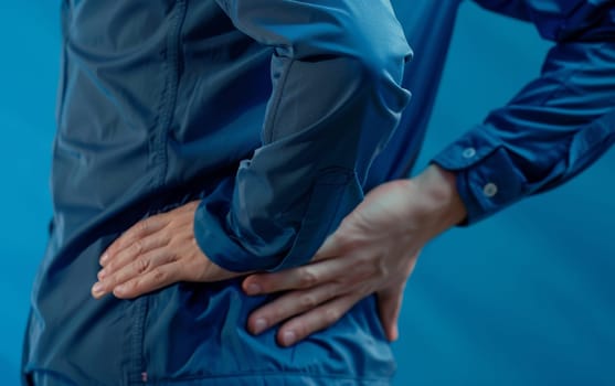 A person in pain, clutching their lower back. The image uses a clinical blue tone to symbolize chronic back pain and discomfort