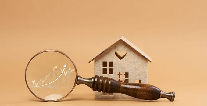 Wooden house and a magnifying glass, representing the concept of real estate purchase, rental growth, and mortgage interest