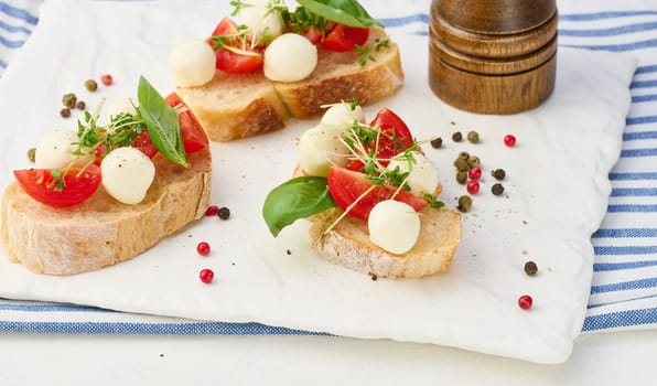 Round mozzarella, cherry tomatoes and microgreens on a piece of white bread, a healthy sandwich, close up