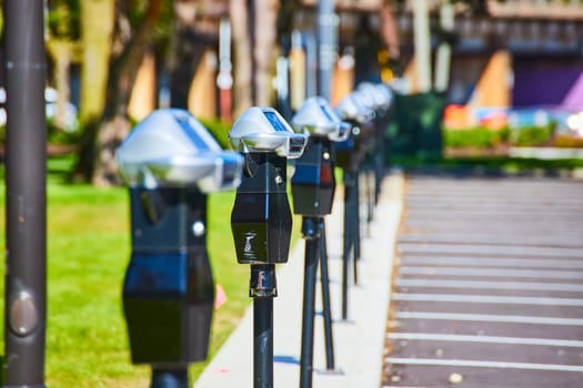 Modern digital parking meters line a vibrant urban park in downtown Fort Wayne, blending technology with green spaces.