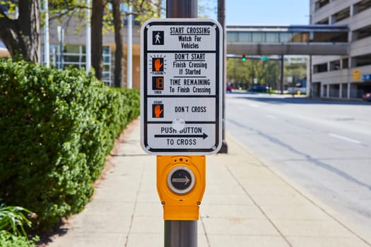 Sunny day in Fort Wayne: pedestrian crossing signal with countdown, urban backdrop.