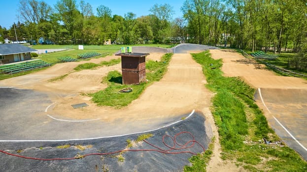 Aerial view of a sunlit BMX track in Warsaw, Indiana, featuring ramps, a judge's booth, and spectator bleachers.