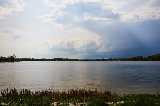 Serene Winona Lake under stormy skies, capturing nature's tranquility and drama in Warsaw, Indiana.