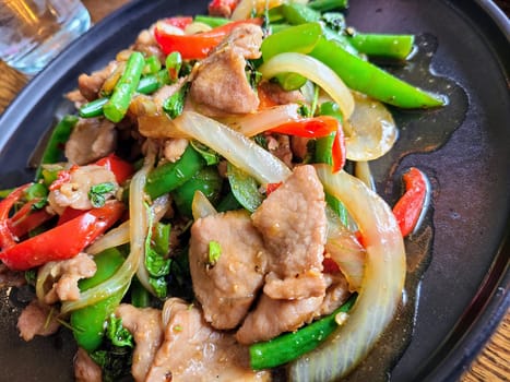 Savory stir-fried pork with snap peas and red peppers on a sleek plate, vibrant and inviting.