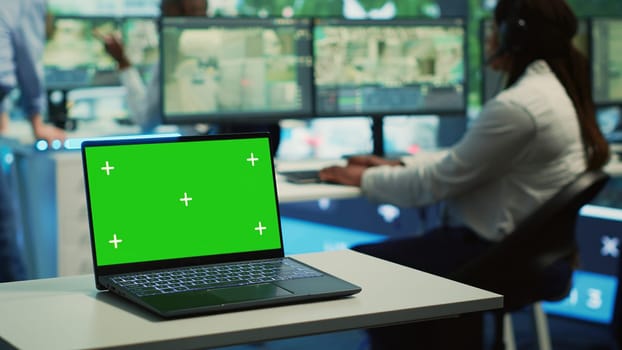 A laptop running isolated mockup display in a monitoring room, people working with surveillance footage from CCTV security cameras around the city. Greenscreen in a government agency. Camera A.