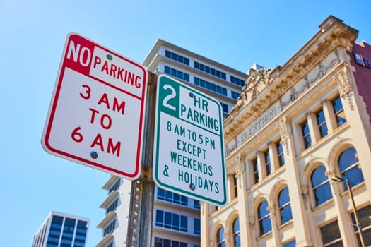 Parking signs in downtown Fort Wayne blend historic and modern architecture, enforcing city life rules.