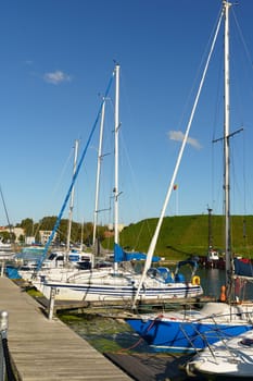 Klaipeda, Lithuania - August 11, 2023: A group of sailboats are secured to a pier, their masts reaching towards the sky as they rest on calm waters.