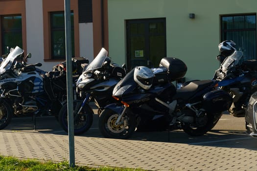 Klaipeda, Lithuania - August 11, 2023: A line of motorcycles neatly parked side by side in a parking lot, displaying various models and colors.