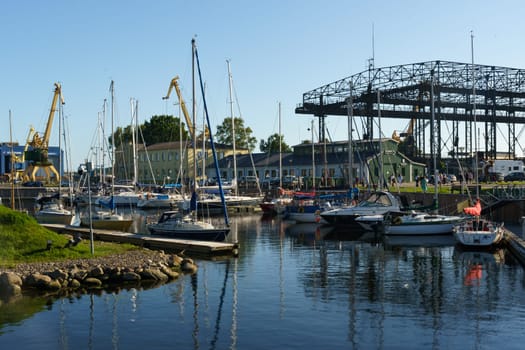 Klaipeda, Lithuania - August 11, 2023: Numerous boats are docked in a bustling harbor next to a bridge, showcasing a busy maritime scene.