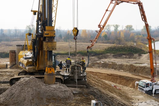 Bobruisk, Belarus - October 29, 2022: A busy construction site where a truck and crane are working on bridge reconstruction with excavation equipment.