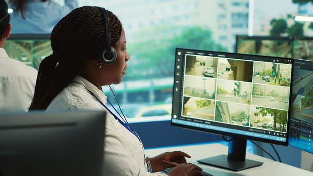African american employee monitoring traffic activity in the city by using CCTV system to ensure public safety. Woman watches real time surveillance footage in government observation room. Camera A.