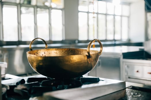 A professional kitchen in a modern restaurant features a shiny metal bowl atop the stove. Clean arrangement of chrome appliances equipment and new furniture. Bright gas service is working.