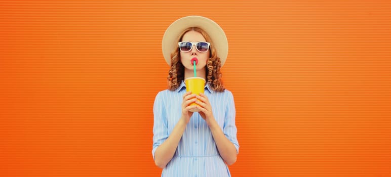 Summer portrait of beautiful caucasian young woman with cup of coffee or fresh juice wearing white straw hat on studio blue background