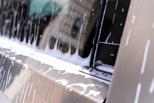 Denver, Colorado, USA-May 5, 2024-A close-up view of a Tesla Cybertruck covered in soap suds during a car wash, showcasing the flowing patterns over its angular surface and highlighting the unique design of the vehicle body.