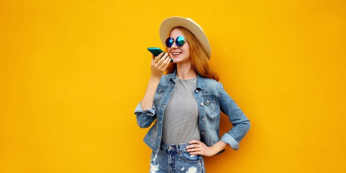 Happy young woman holding talking on the phone, using voice command recorder, assistant or takes calling wearing casual clothing on colorful yellow background