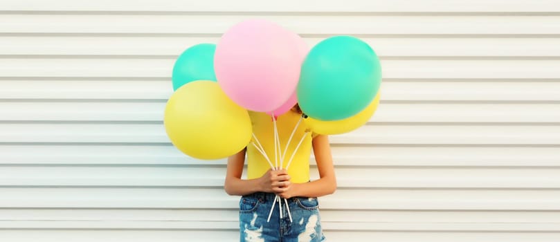 Summer, holiday, celebration, happy cheerful woman covering her head with bright colorful balloons having fun on white background