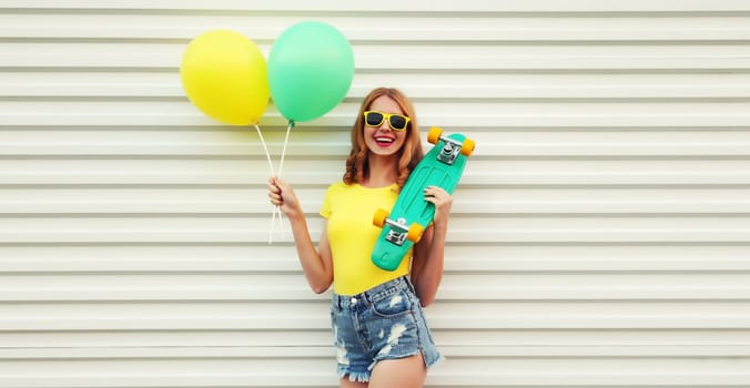 Summer, holiday, celebration, happy cheerful young woman with bright colorful balloons having fun with skateboard on white background