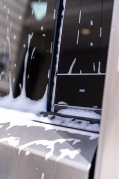 Denver, Colorado, USA-May 5, 2024-A close-up view of a Tesla Cybertruck covered in soap suds during a car wash, showcasing the flowing patterns over its angular surface and highlighting the unique design of the vehicle body.