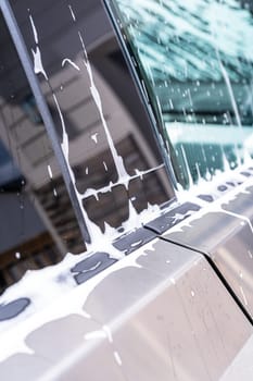 Denver, Colorado, USA-May 5, 2024-A close-up view of a Tesla Cybertruck covered in soap suds during a car wash, showcasing the flowing patterns over its angular surface and highlighting the unique design of the vehicle body.