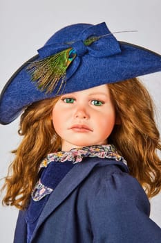 Young doll in elegant blue hat with peacock feather, embodying sophistication and style