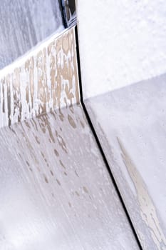 Denver, Colorado, USA-May 5, 2024-This image captures soapy water streaming beautifully down the metallic, angular side of a Tesla Cybertruck during a wash. The close-up showcases the sleek lines and unique design of the vehicle.