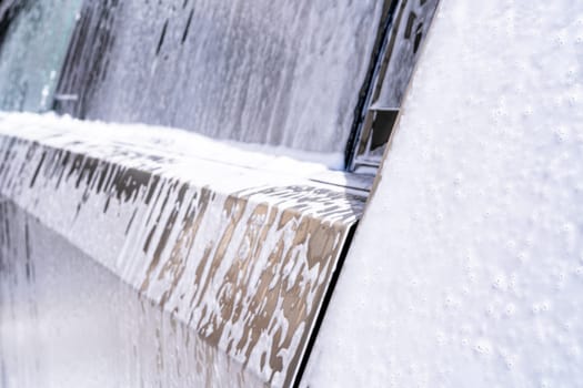 Denver, Colorado, USA-May 5, 2024-This image captures soapy water streaming beautifully down the metallic, angular side of a Tesla Cybertruck during a wash. The close-up showcases the sleek lines and unique design of the vehicle.