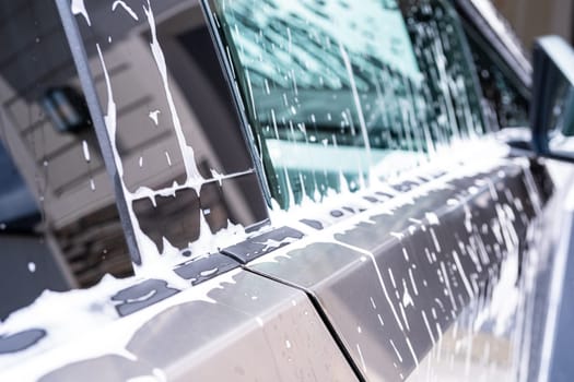 Denver, Colorado, USA-May 5, 2024-A close-up view of a Tesla Cybertruck covered in soap suds during a car wash, showcasing the flowing patterns over its angular surface and highlighting the unique design of the vehicle body.