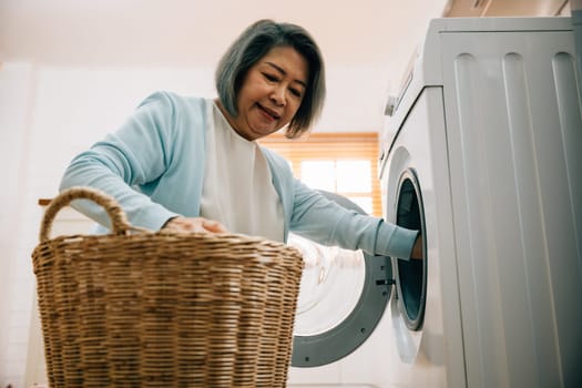 An old woman, a grandmother, loads laundry into the washing machine, smiling as she covers her routine. This portrait reflects a modern solution for family hygiene and happiness.