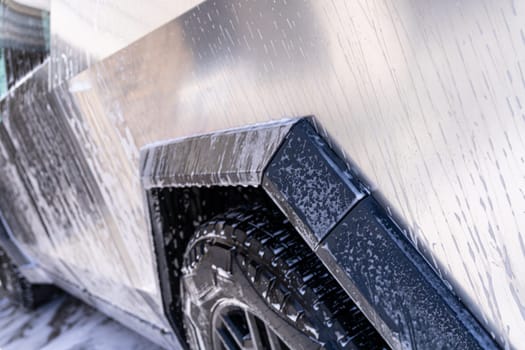 Denver, Colorado, USA-May 5, 2024-This image features a close-up view of the Tesla Cybertruck wheel and angular body design covered in soap and water during a thorough car wash, highlighting the unique textures and robust details of the electric truck.