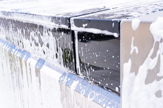 Denver, Colorado, USA-May 5, 2024-This image captures a detailed view of soap suds accumulating and dripping off the edge of a Tesla Cybertruck window during a wash, highlighting the vehicle distinct, clean lines and reflective surfaces.