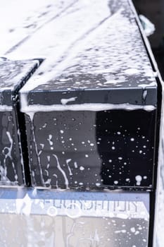 Denver, Colorado, USA-May 5, 2024-This image captures a detailed view of soap suds accumulating and dripping off the edge of a Tesla Cybertruck window during a wash, highlighting the vehicle distinct, clean lines and reflective surfaces.