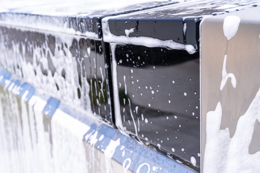 Denver, Colorado, USA-May 5, 2024-This image captures a detailed view of soap suds accumulating and dripping off the edge of a Tesla Cybertruck window during a wash, highlighting the vehicle distinct, clean lines and reflective surfaces.