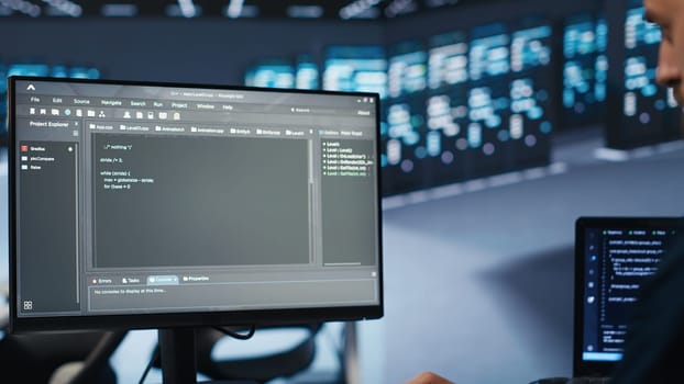 System administrator running script on computer screen in high tech data center, ensuring optimal performance. Worker monitoring energy consumption, doing checkup on server rackmounts clusters