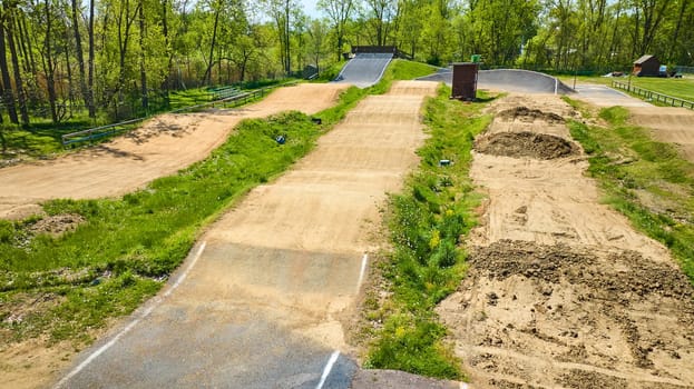 Aerial view of a serene BMX track in Warsaw, Indiana, nestled among lush greenery on a sunny day.