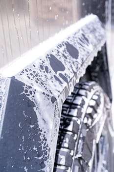 Denver, Colorado, USA-May 5, 2024-This image features a close-up view of the Tesla Cybertruck wheel and angular body design covered in soap and water during a thorough car wash, highlighting the unique textures and robust details of the electric truck.